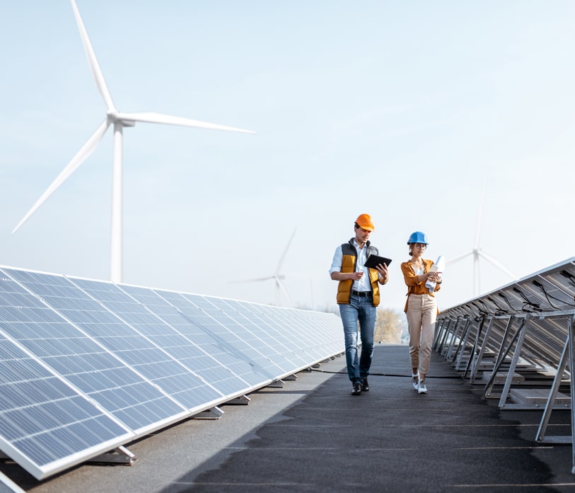 Two engineers are walking alongside solar panels